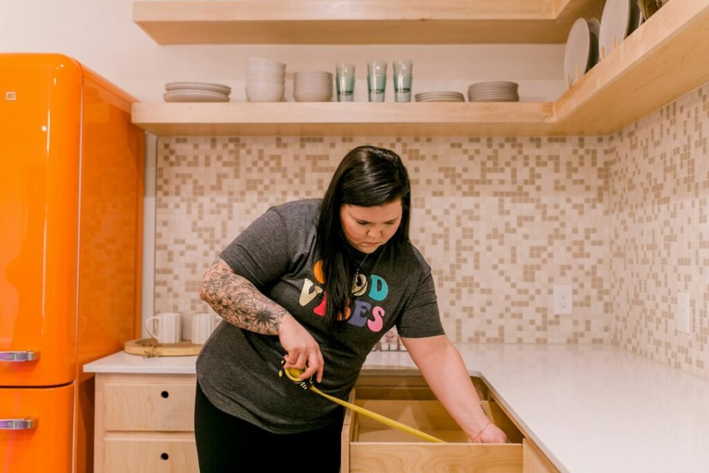 A kitchen drawer being measured with a tape measure before choosing an appliance